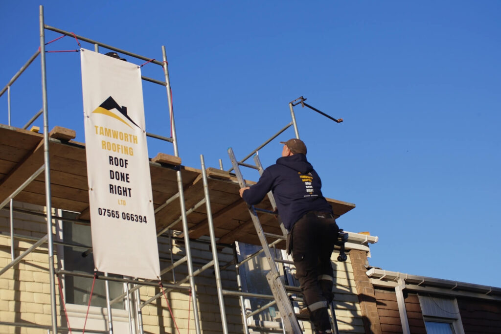 Roofer claiming the lather to reach top of scaffolding. Blue sky in the background.